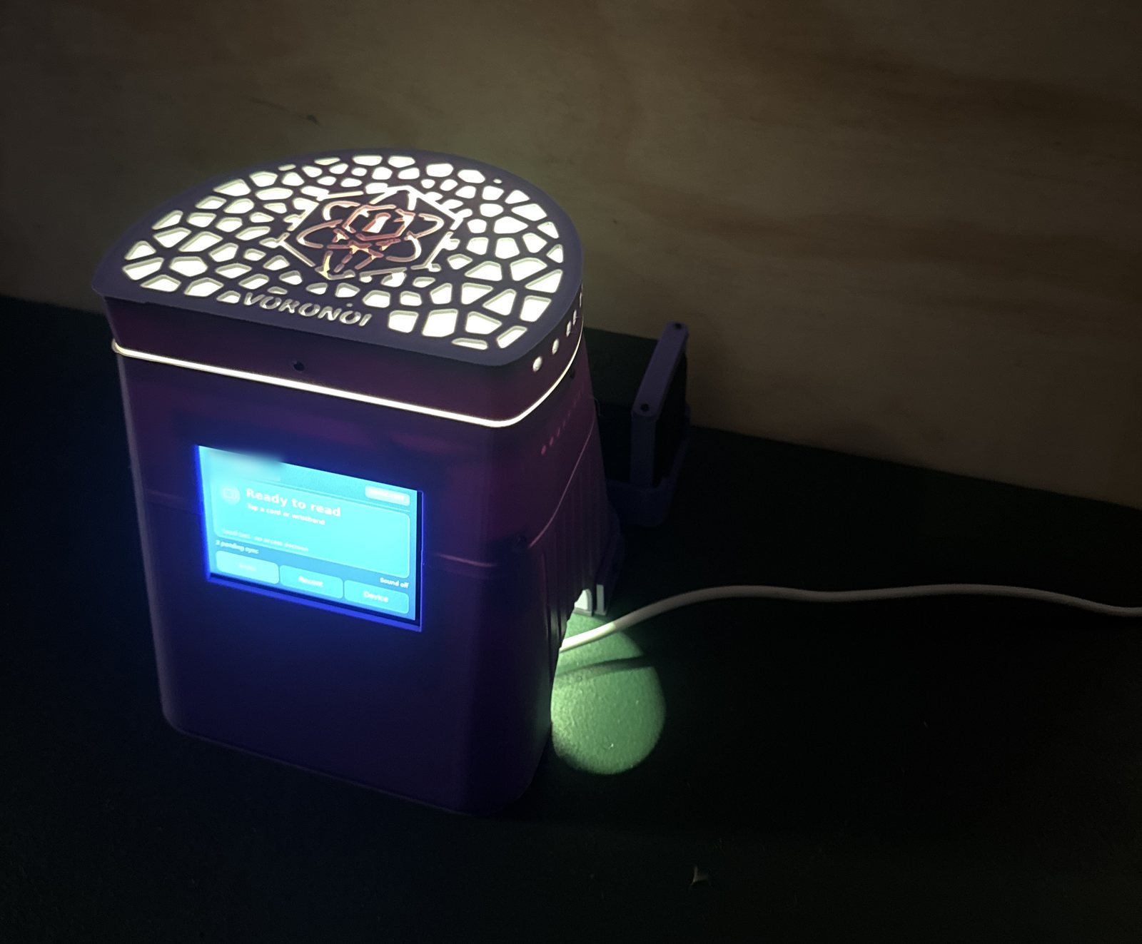 The same kiosk with the room lights off, lid glowing